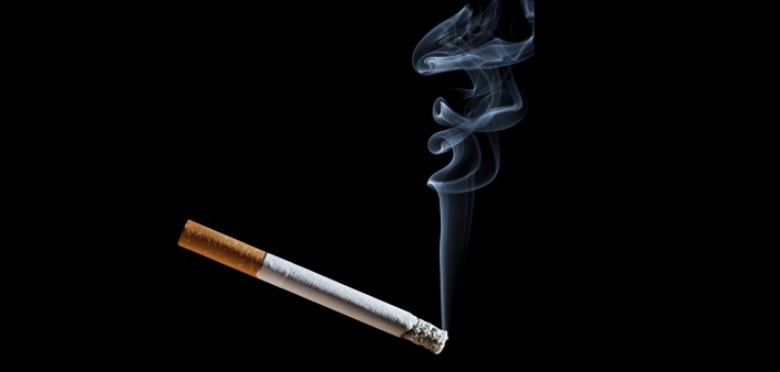 Cigarette with blue smoke on black background