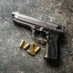 9mm pistol bullets and handgun on black table.
