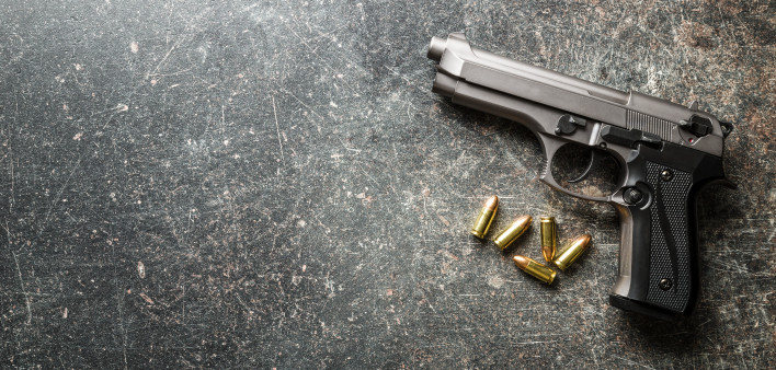9mm pistol bullets and handgun on black table.