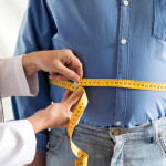doctor measuring mans stomach