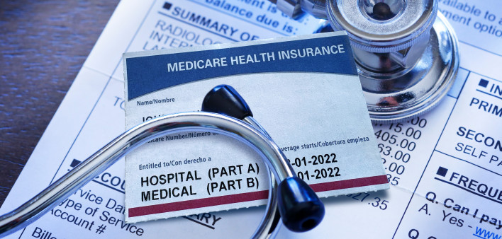 A Medicare insurance card and a stethoscope rest on top of a hospital medical invoice.
