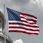 American flag waving with the Capitol Hill in the background