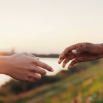 African and caucasian women reaching out their hands to each other