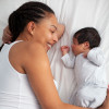 frican-American mother having fun with cute baby boy on the bed