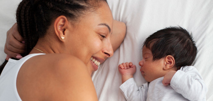 frican-American mother having fun with cute baby boy on the bed