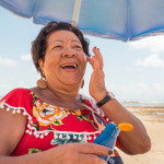 Senior woman using a suntan lotion on the beach