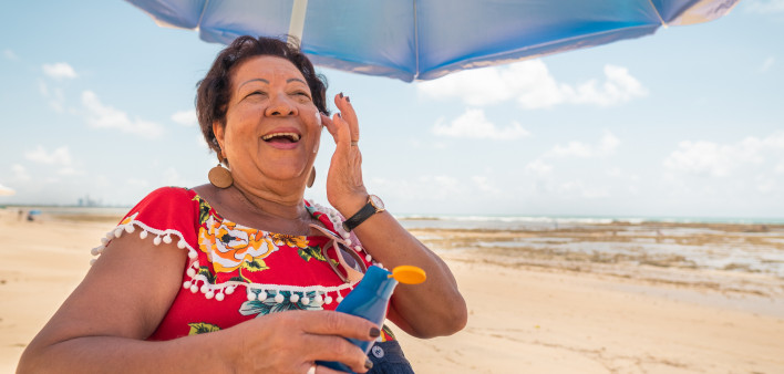 Senior woman using a suntan lotion on the beach