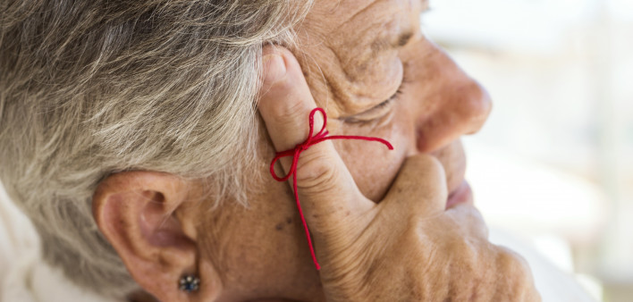 old woman with red string tied around index finger