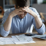 Sad depressed man checking bills, anxiety about debt or bankruptcy