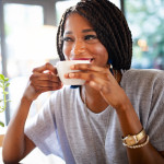 Beautiful young african woman enjoying a cup of coffee in coffee shop