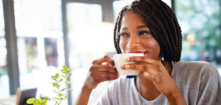 Beautiful young african woman enjoying a cup of coffee in coffee shop