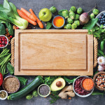 Healthy food selection with fruits, vegetables, seeds, super foods, cereals and the cutting board in the middle