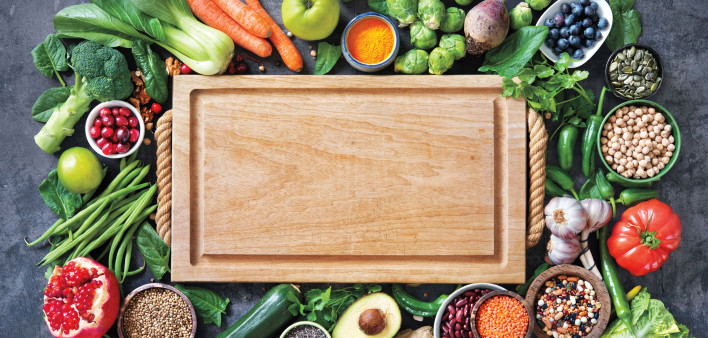Healthy food selection with fruits, vegetables, seeds, super foods, cereals and the cutting board in the middle