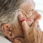 old woman with red string tied around index finger