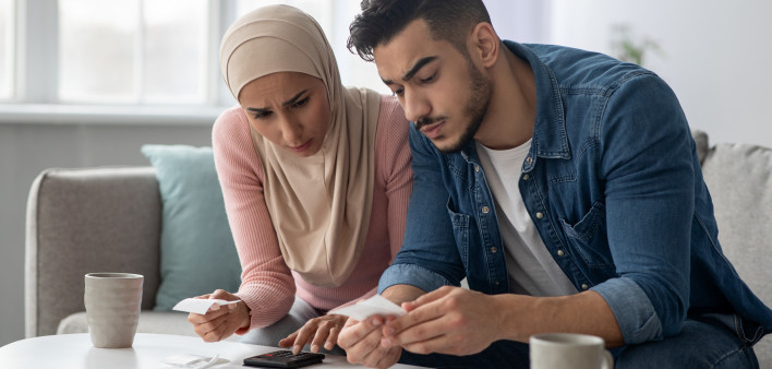 Confusded lady in hijab and her upset husband with bills