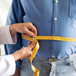doctor measuring mans stomach