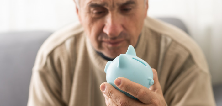 Senior caucasian man holding piggy bank with glasses depressed and worry for distress, crying angry and afraid.