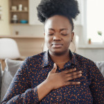 Pressure in the Chest. Close-up Photo of a Stressed Obese African American Woman Who Is Suffering From a Chest Pain and Touching Her Heart Area.