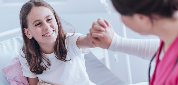 High angle of girl with plush toy smiling and giving a high five with nurse in the hospital