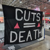 “Cuts Equal Death” banner at AIDS 2026