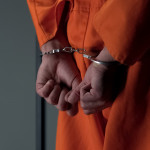 Prisoner with handcuffed arms behind back, another jail transfer, criminal