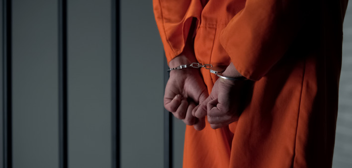 Prisoner with handcuffed arms behind back, another jail transfer, criminal