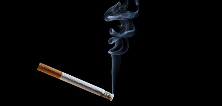 Cigarette with blue smoke on black background