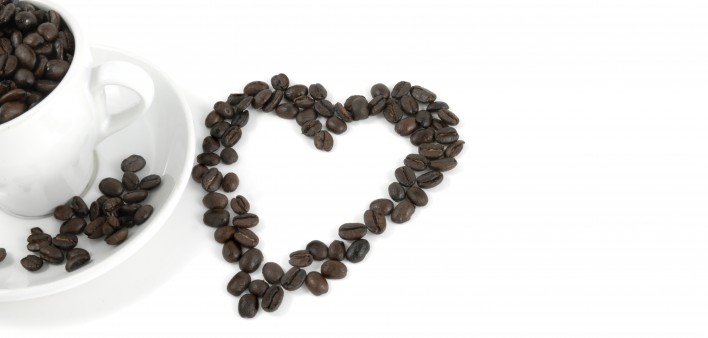 cup of coffe and coffee beans arranged in the shape of a heart