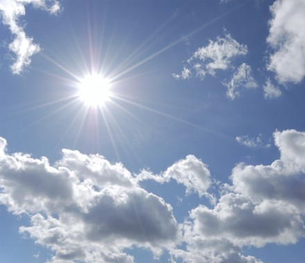 bright sun shining in blue sky with white clouds