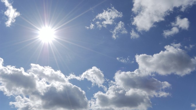bright sun shining in blue sky with white clouds