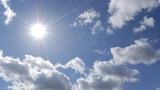 bright sun shining in blue sky with white clouds