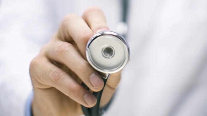 a doctors hand holding up a stethoscope