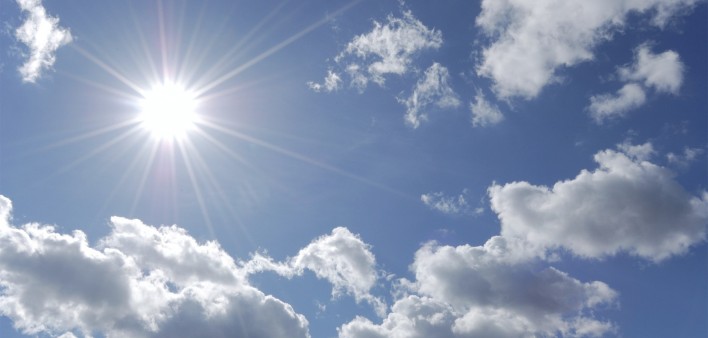 bright sun shining in blue sky with white clouds