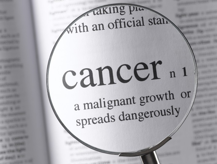a magnifying glass magnifying the definition of cancer in a dictonary