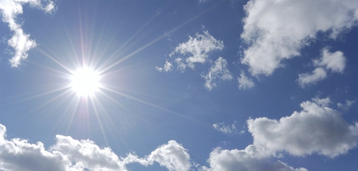 bright sun shining in blue sky with white clouds
