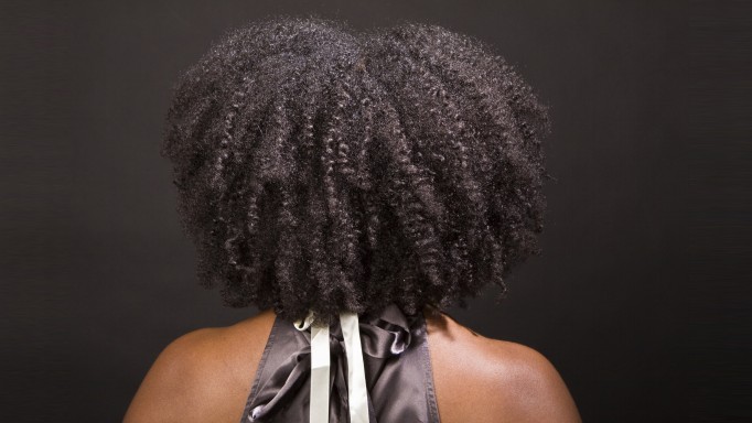 the back of an African American woman's head showing her curly afro and bare shoulders