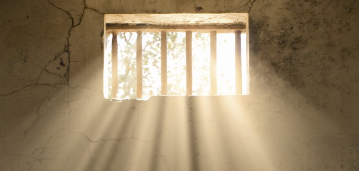 light shining through bars of prison window 