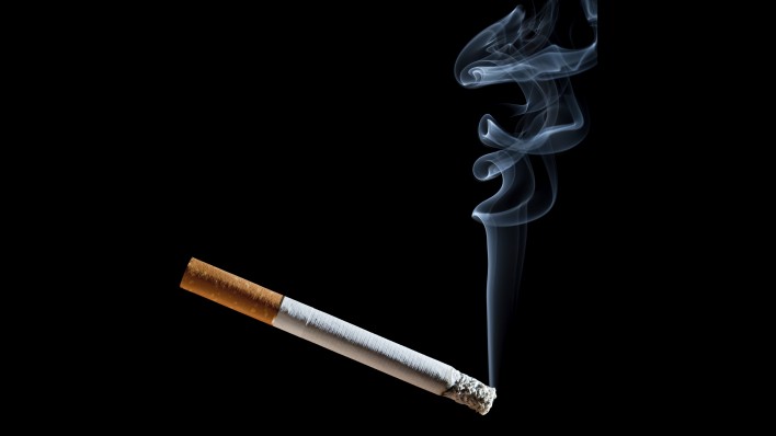 Cigarette with blue smoke on black background