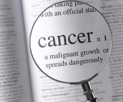 a magnifying glass magnifying the definition of cancer in a dictonary
