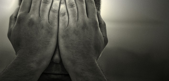 a black and white image of a man holding his hands over his face