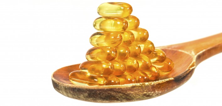 Vitamin D Capsules on wooden spoon