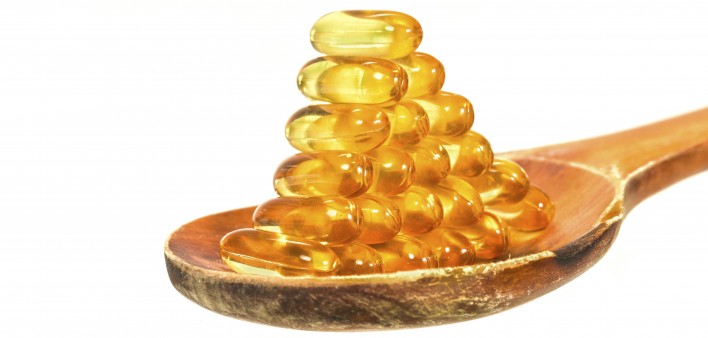 Vitamin D Capsules on wooden spoon