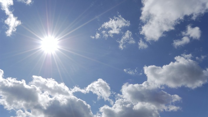 bright sun shining in blue sky with white clouds