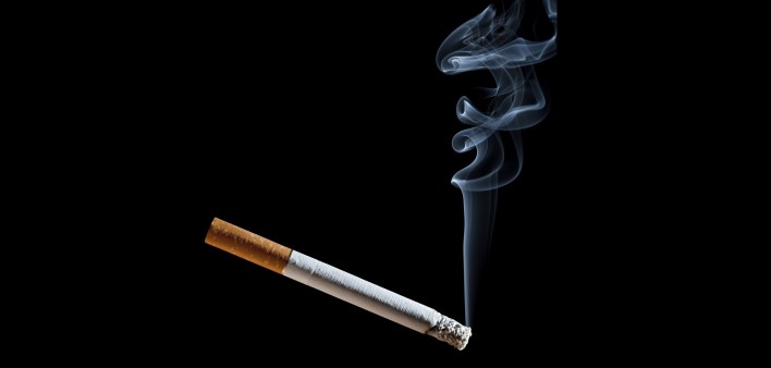 Cigarette with blue smoke on black background
