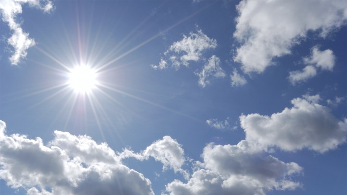 bright sun shining in blue sky with white clouds