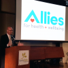 Sean DeYoung, CEO of Allies for Health + Wellbeing, unveils the new logo.