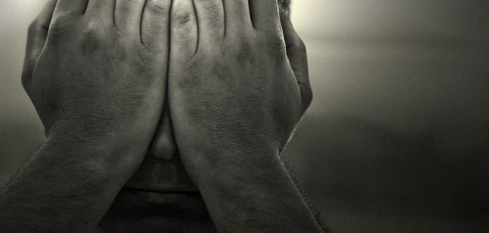 a black and white image of a man holding his hands over his face