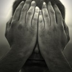 a black and white image of a man holding his hands over his face