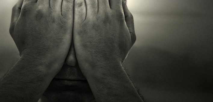 a black and white image of a man holding his hands over his face
