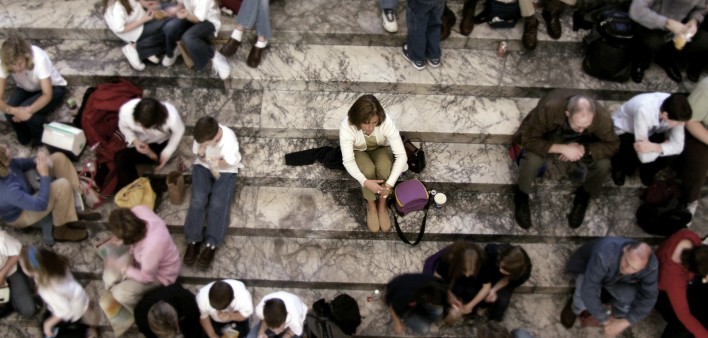 woman sitting on the stairs, alone in a crowd